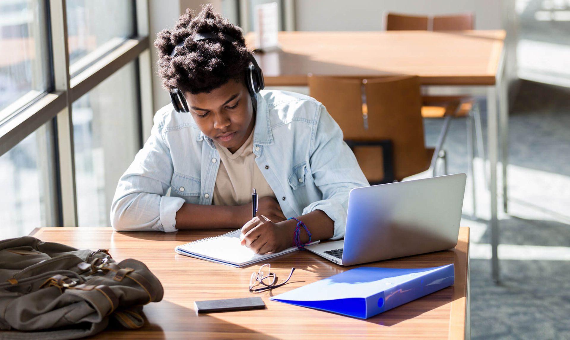 Student doing homework while listening to headphones.